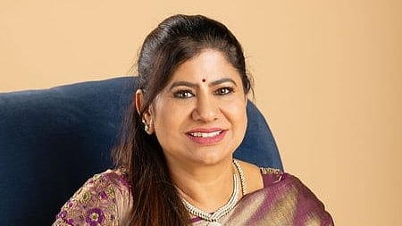 In the image Leema Rose Martin is shown smiling at camera she is wearing a saree and sitting in a sofa