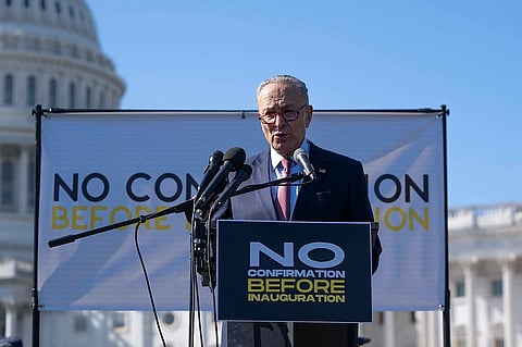 Senate Minority Leader Chuck Schumer speaks at a podium. The U.S. Capitol building is visible in the background.