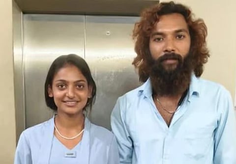 Image of Monalisa and Farman Khan standing side by side, both smiling slightly in front of a metal elevator. They wear light blue shirts, conveying a casual atmosphere.
