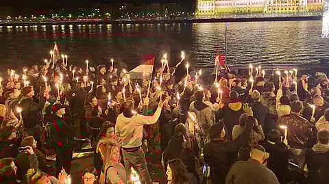 A crowd holding up candles and Hungarian flags in Budapest