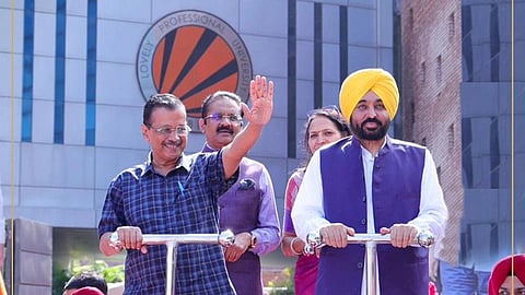 Arvind Kejriwal, Bhagwant Mann and Ashok Mittal standing in front of the LPU logo
