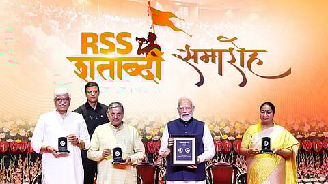Narendra Modi and others stand in front of a board reading 'RSS Shatabdi'