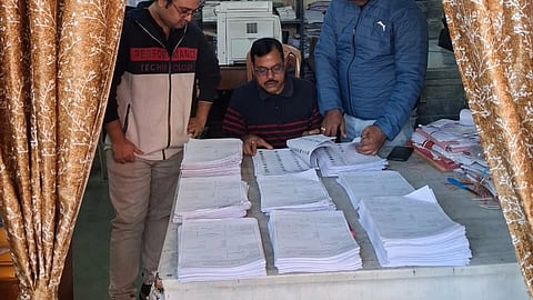 lots of forms stacked up infront of 3 officers