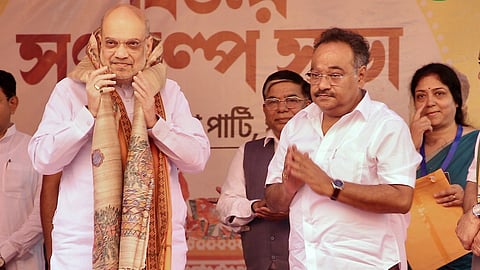 Samik Bhattacharya stands next to Amit Shah on an orange stage