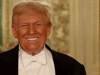 Image of Trump smiling warmly in a formal setting, wearing a tuxedo with a white bow tie. The background is elegant, featuring ornate, light-colored decor.