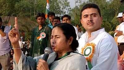 Mamata Banerjee speaking into a mic next to Suvendu Adhikari 