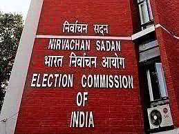 Red brick wall with white text reads "Election Commission of India" in English and Hindi, conveying an official and authoritative tone.