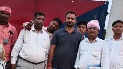 In the image one person is shown in black with many other posing for a picture outside a police station