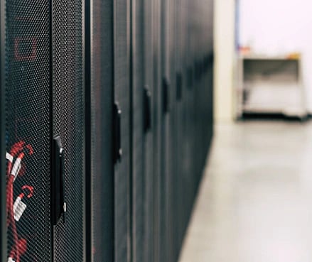A row of black server racks extends into the distance in a data center. The polished floor reflects light, creating a clean and organized atmosphere.