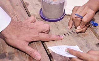 Hands of two people are shown with one hands inking other persons finger showing election voting