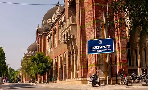 A red brick building with a dome and a blue sign reading 'faculty of arts'