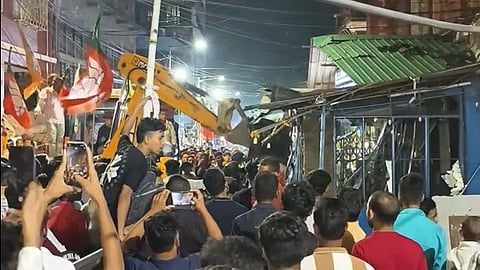 A crowd in front a bulldozer with BJP flags