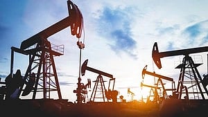 Oil pumps silhouetted against a colorful sunset sky, representing energy production. The scene conveys industry and tranquility.