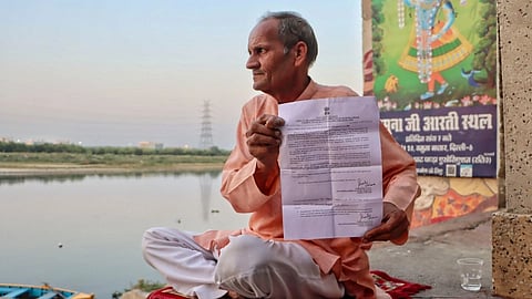 A man hold up a govt notive in front of a river