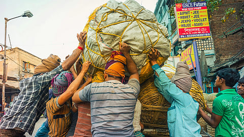labours colorful clothing and turbans work together to secure a large, rope-tied load on a truck in a busy street, conveying teamwork