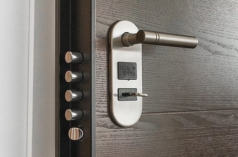 A sturdy metal door with a sleek silver handle and a key inserted in the keyhole. Four visible locking bolts suggest enhanced security.