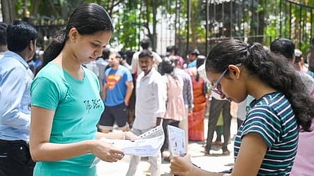 In the image many students are shown outside the exam centre two are seen taking out their documents