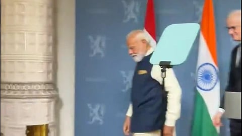 narendra modi walking off stage with the Indian flag in the background