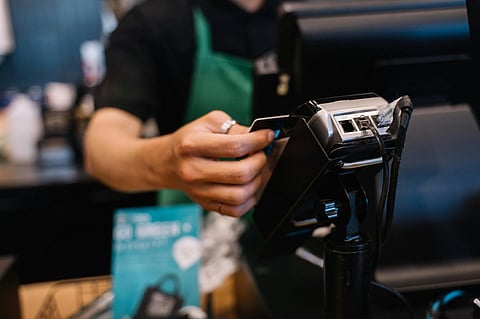 In the image a cafe is shown with a credit card swipe machine and a credit card