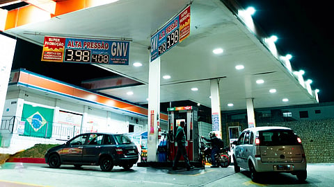 Cars lined up at a gas station displaying sharply increased fuel prices amid the global oil crisis