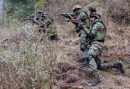 Four Army officers in a grass covered area with guns