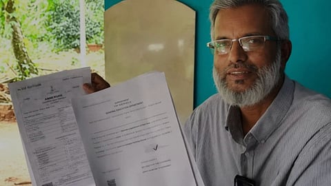 Abdul Majeed, 61, from Keralam, holds an offer letter for a government job, wearing glasses and smiling.
