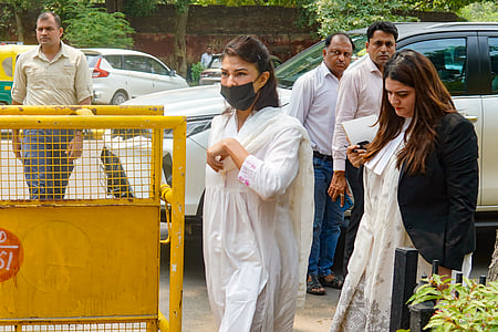 In the image Jacqueline Fernandez is shown withh a lawyer and other government officials