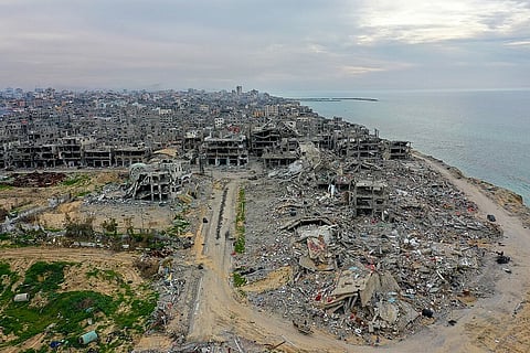Aerial view of a coastal city devastated by conflict. Collapsed buildings and rubble dominate the landscape, conveying destruction and desolation.