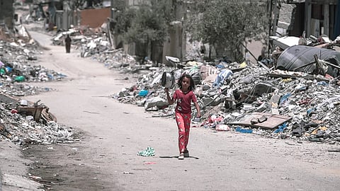 A girl walks through the wreckage of a devastated Gaza neighborhood, looking for food amidst the destruction of war.