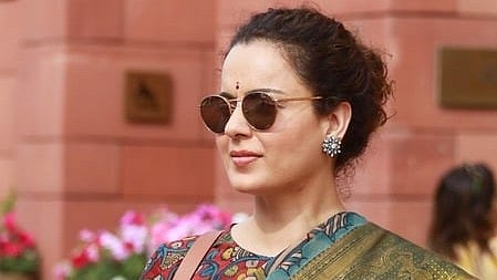 In the image Kangana Renaut is shown outside parliament wearing sun glasses and a saree