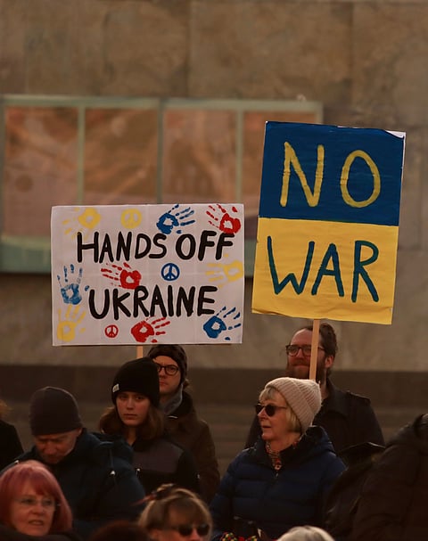 Protesters of various backgrounds display signs stating "No War," expressing their collective desire for peace and harmony.