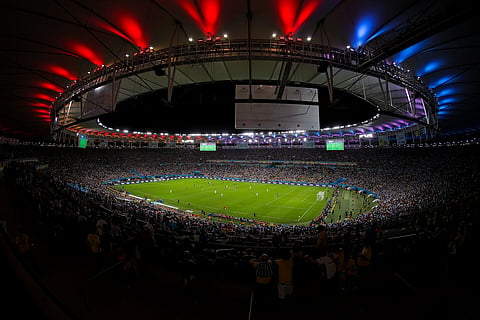 Wide-angle view of a packed soccer stadium at night, with vibrant red, blue, and white lights illuminating the roof, creating an electrifying atmosphere. The final match of World Cup 2014 between Germany and Argentina 2014-07-13