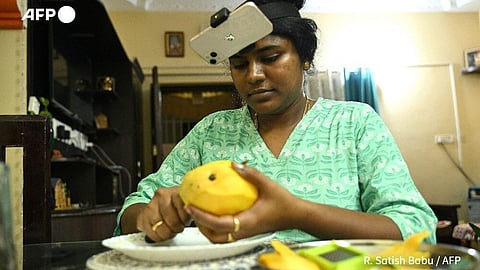 An Indian woman wearing a head-mounted camera slices a mango