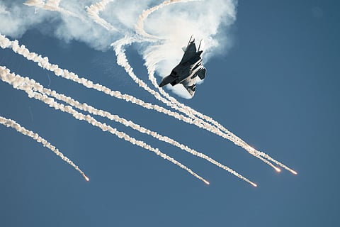 A jet aircraft soaring through the sky, trailing white smoke behind it.