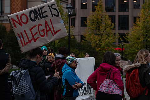  A diverse group of people stands on a street, holding various signs advocating for social change and justice.