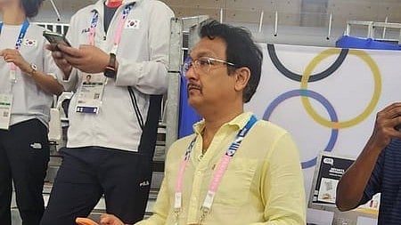 In the image coach Jaspal Rana is shown behind him are other staff of olympics and olympics sign
