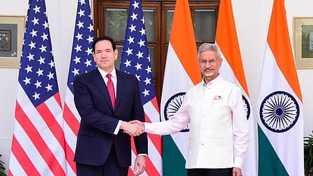 In the image Marco Rubio is shown shaking hands with S. Jaishankar behind them are six flags with three Indian flags and three US flags
