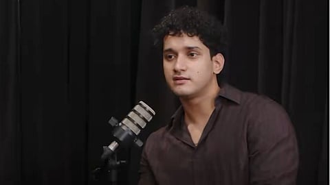 Saurav Das positioned before a microphone, indicating he is about to engage in a speaking or recording activity.