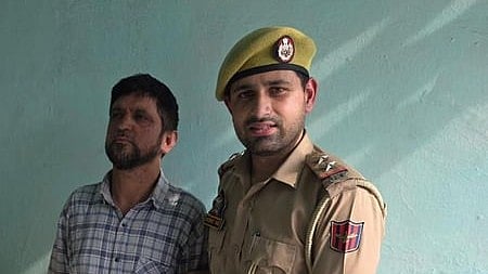 In the image a police officer is shown with a person standing beside him in checked shirt