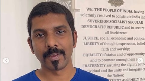 Vinay Kuma, man with beard and mustache looks in the camera with preamble of Indian constitution in the background