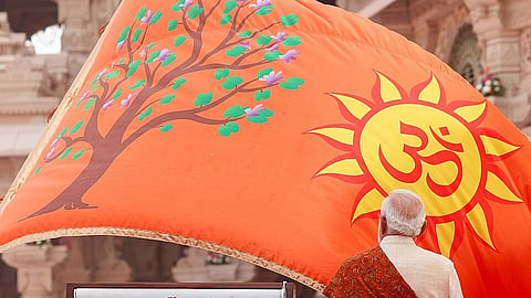 Narendra Modi is positioned next to a large hindu saffroflag, emphasizing its bold color and presence in the scene.