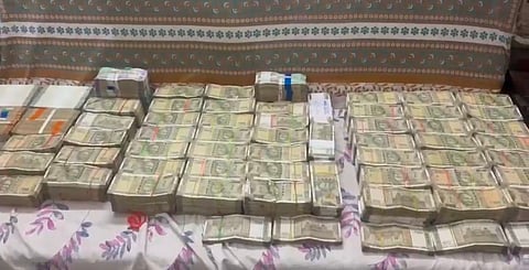Stacks of cash in Indian rupee laid out on a mattress as part of ACB raid.