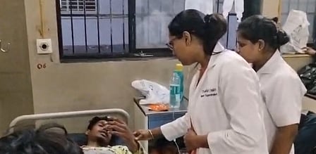In the image a patient is shown in the bed and two female doctors are examining him