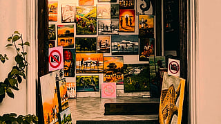 A warmly lit archway showcases a variety of colorful paintings on either side of the entrance, creating a vibrant and inviting artistic display.