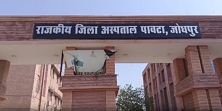 Entrance of a government district hospital in Jodhpur with a sign in Hindi. The brick building under a clear sky conveys an official tone.