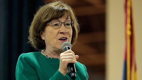 In the image Susan Collins is shown adressing the people she is holding a mic