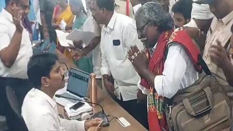 In the image Padma Shri awardee Darshanam Mogilaiah is shown joining his hands and pleading in front of a administrative worker  