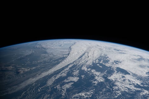 Image of earth from space. In a dark pitch vaccum, a blue earth can be  seen.