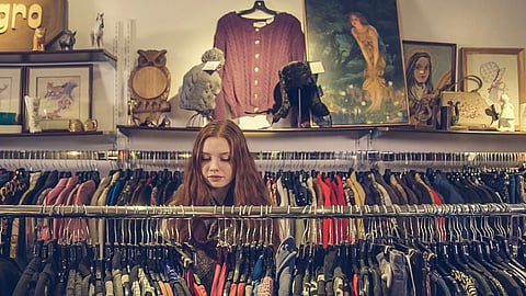 In the image a young girl is shown in a artistic and vintage thrift shop