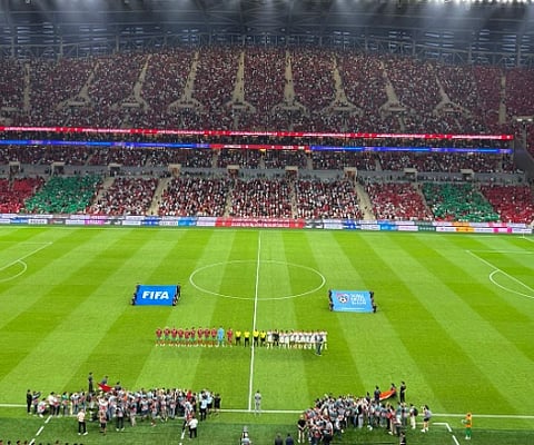 Panoramic view of a vibrant football match in a Moroccan stadium packed with cheering fans.

